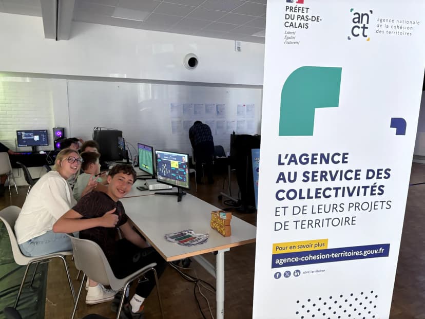 Visiteurs jouant à FC25 sur PC devant un panneau sponsor de l'ANCT - Agence nationale de la cohésion des territoires - lors du Gaming House Tour 2025